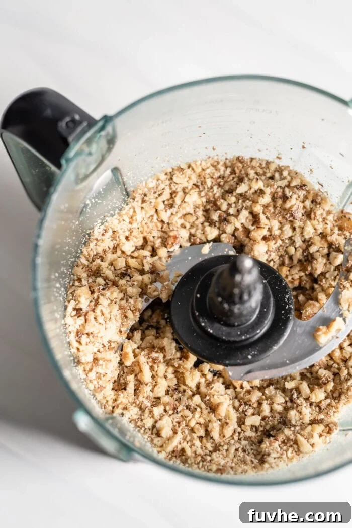 Blended almonds and walnuts in a food processor, resembling a coarse flour.