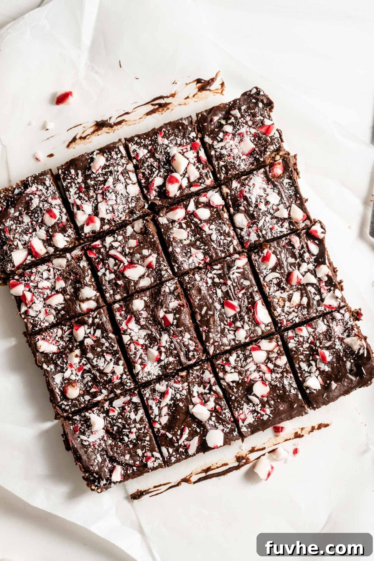 Tray of peppermint brownies sliced into 16 portions on a piece of parchment paper, ready to be served.