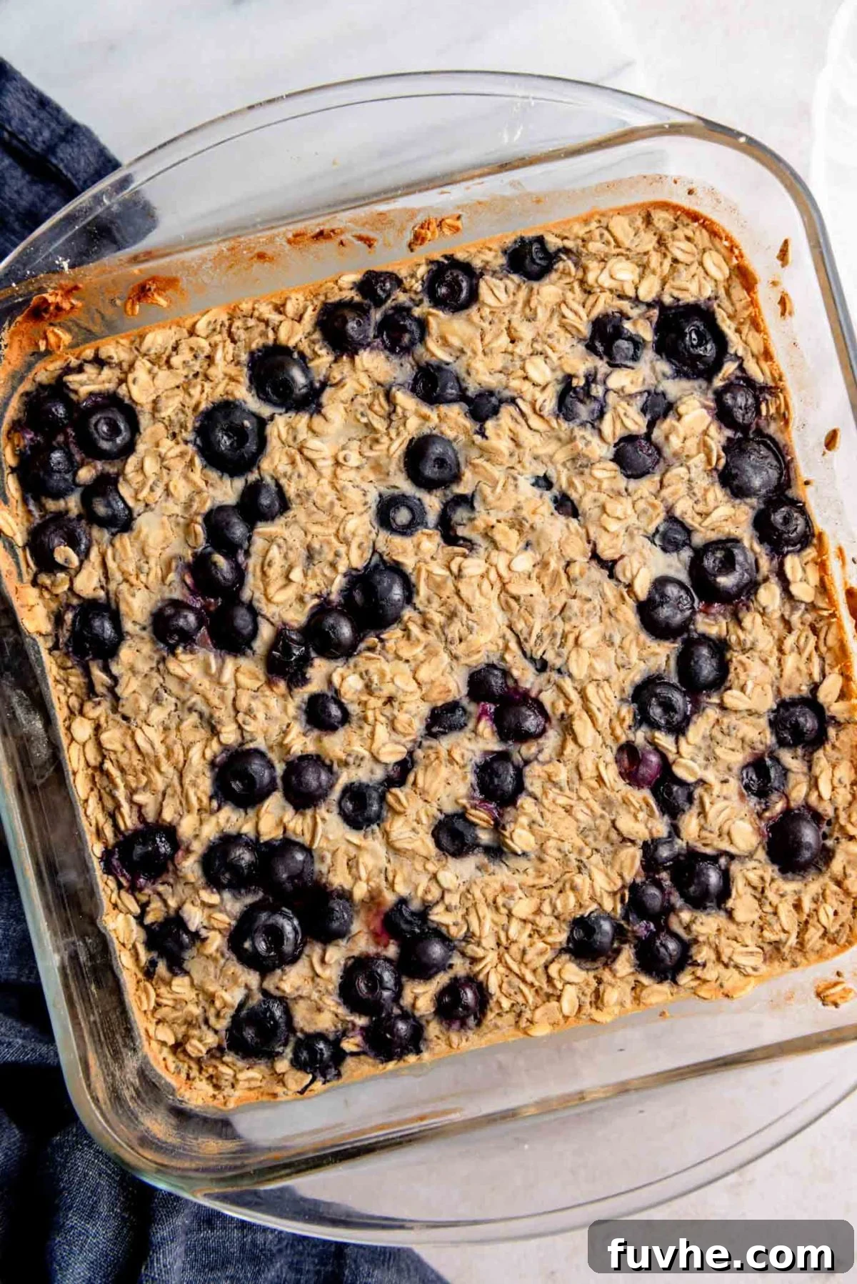Protein-Packed Baked Oats 2 Delicious baked blueberry protein oatmeal in a clear glass baking dish, ready to be served as a healthy breakfast or snack.