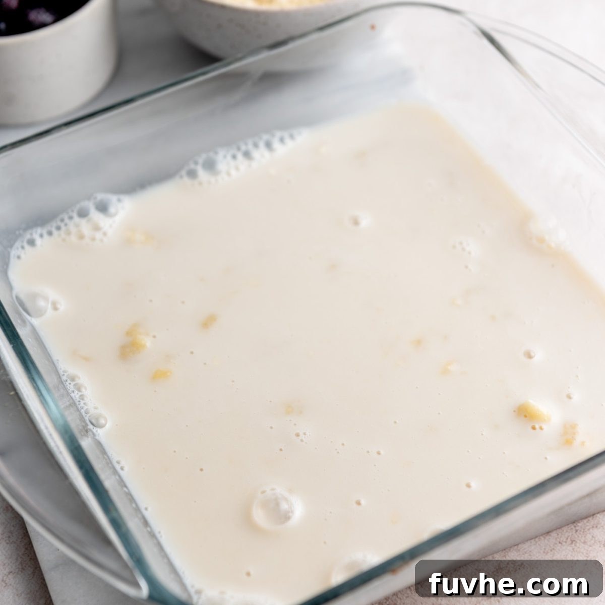 Protein-Packed Baked Oats 5 Plant-based milk and vanilla extract mixed with mashed banana in a glass baking dish.