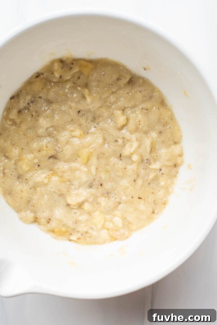 Wholesome Chocolate Protein Baked Oat Bars 3 Mashed ripe banana in a mixing bowl, ready for the next ingredients to be added for the chocolate protein oatmeal bars.