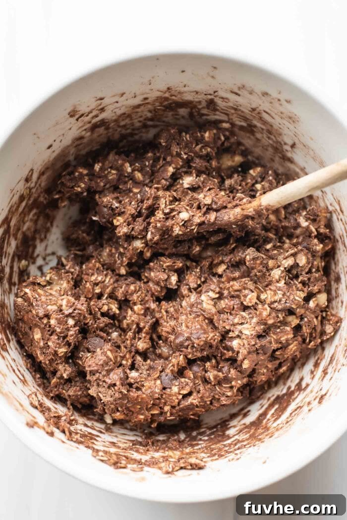 Wholesome Chocolate Protein Baked Oat Bars 4 Thick chocolate batter with dairy-free chocolate chips in a mixing bowl, perfectly mixed for baking the oatmeal bars.