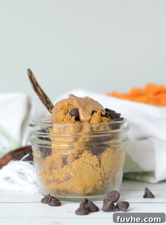 Small jar of cookie dough topped with almond butter and chocolate chips.