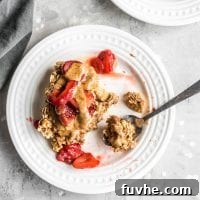 A square of baked apple cinnamon oatmeal topped with strawberries on a plate, a delightful breakfast.