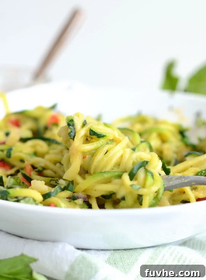 A bowl of zucchini noodles with a fork in it.