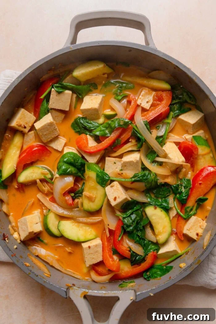 The finished red curry, featuring bell pepper, spinach, tofu, onion, and zucchini, perfectly cooked and vibrant in the pan.