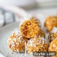 A carrot energy ball with a bit taken out of it on a plate.