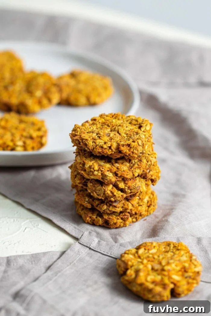 A stack of golden-hued carrot walnut coconut cookies arranged neatly on a dishcloth, ready to be enjoyed.