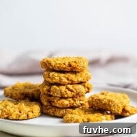 A stack of cookies on a plate with more cookies placed around them.