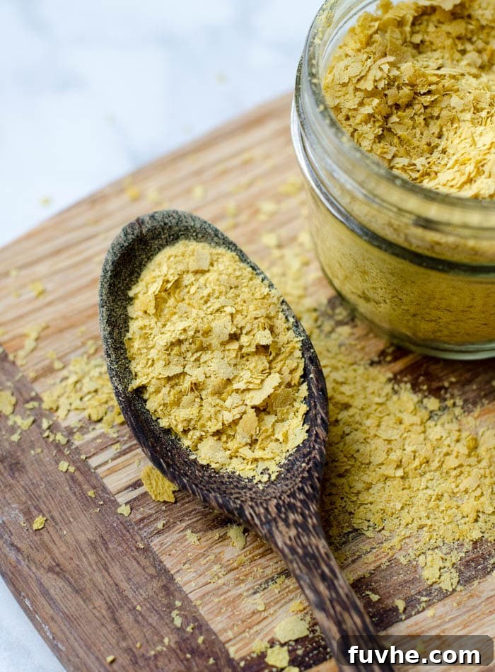 Nutritional Yeast: Your Passport to Cheesy Flavor, Plant-Based Nutrition 3 Nutritional Yeast Health Benefits and Uses - A spoonful of yellow flakes