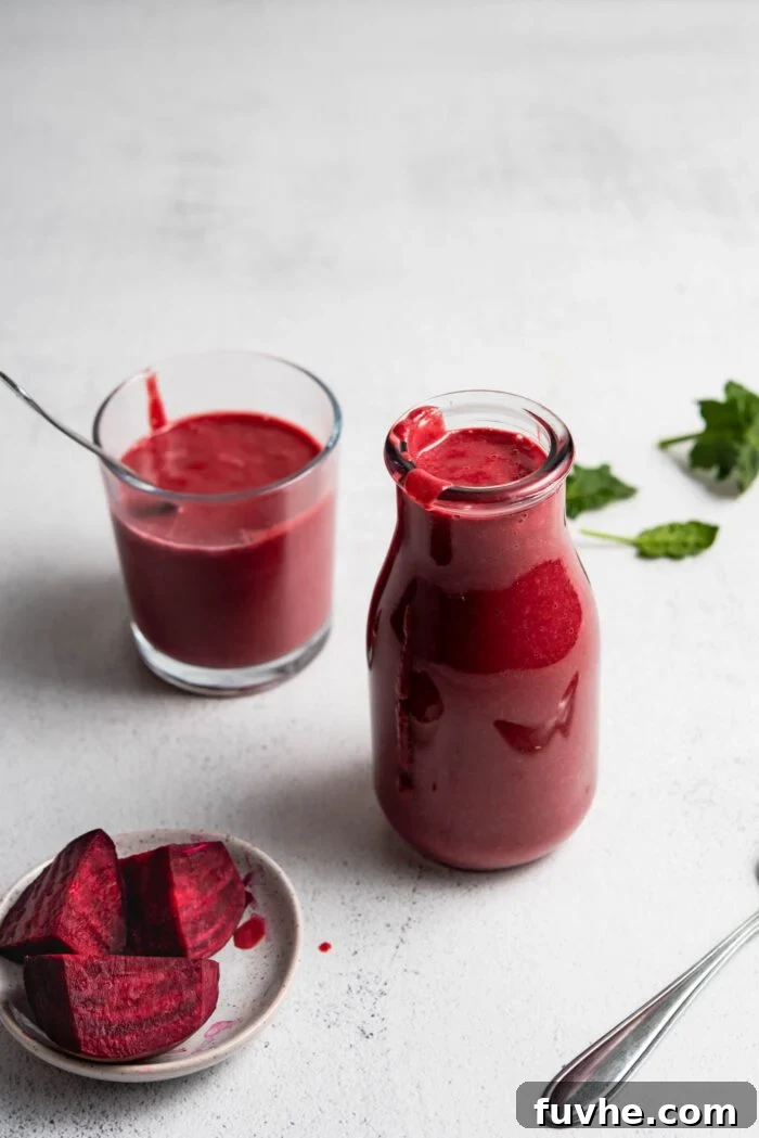 Beet smoothie in a jar with another small glass behind it and a small dish of chopped beets beside it.