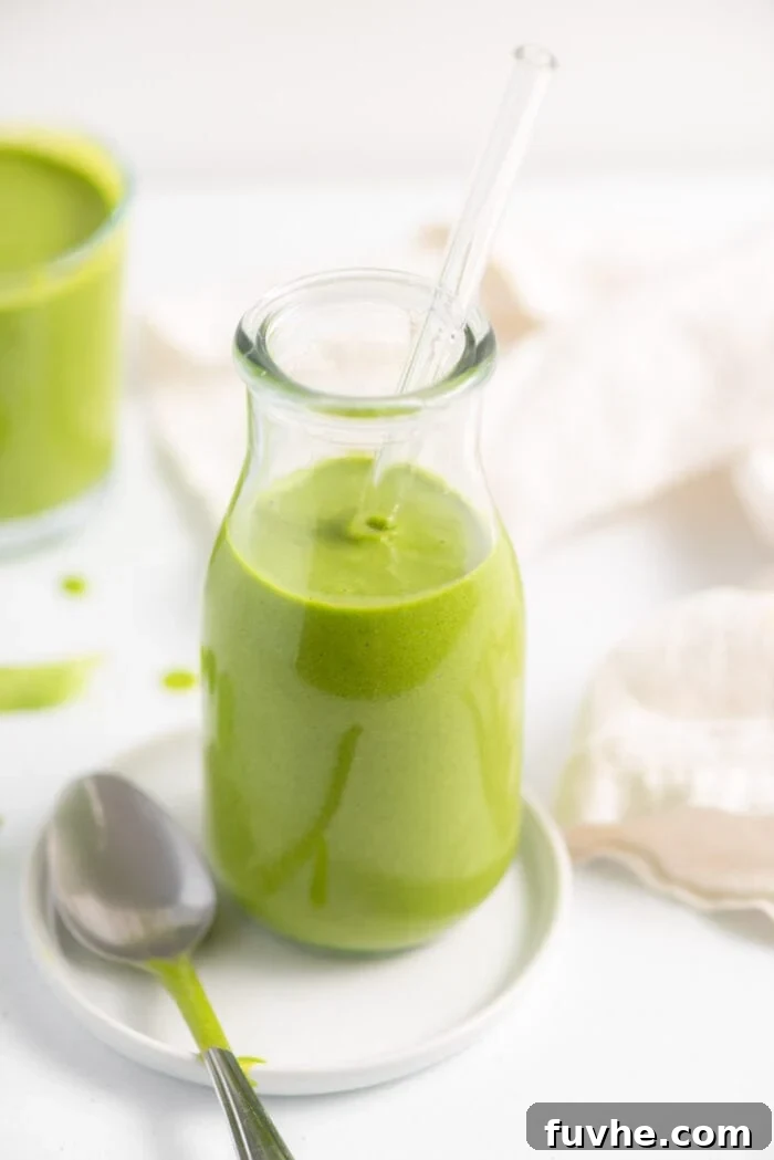 Green smoothie in a jar with another smoothie in the background.