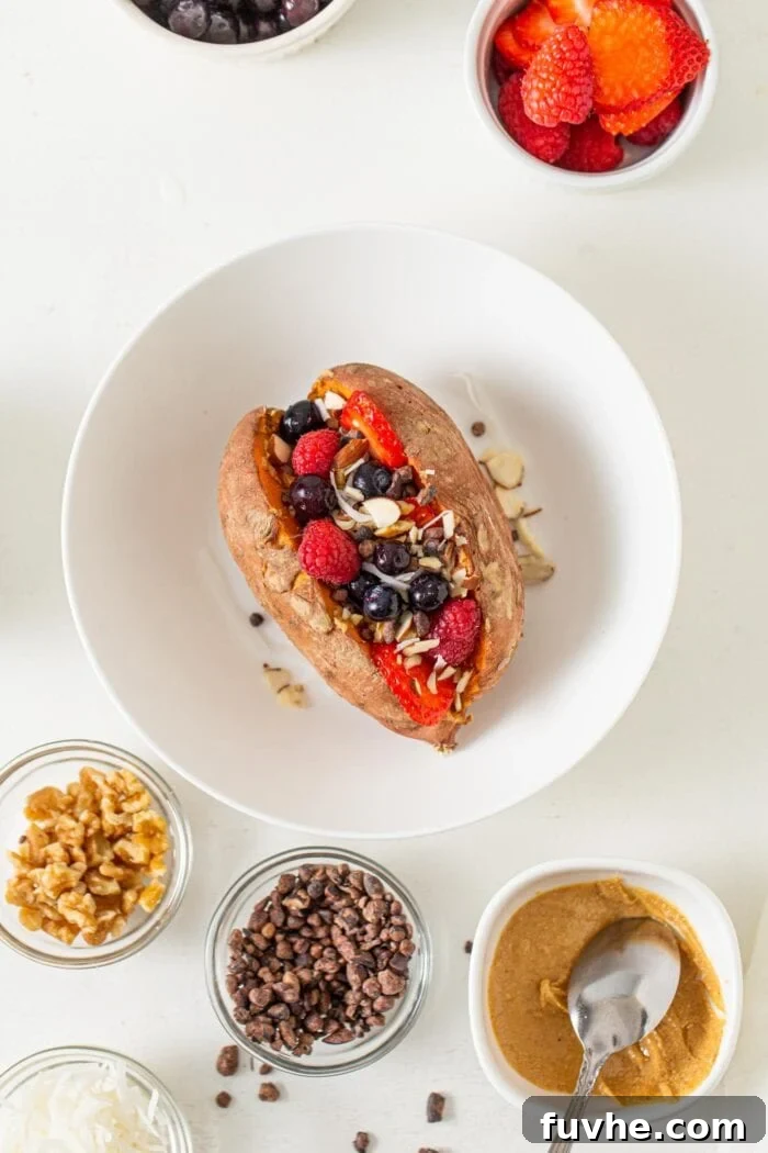Overhead view of a baked sweet potato topped in a bowl with berries, peanut butter and almonds.