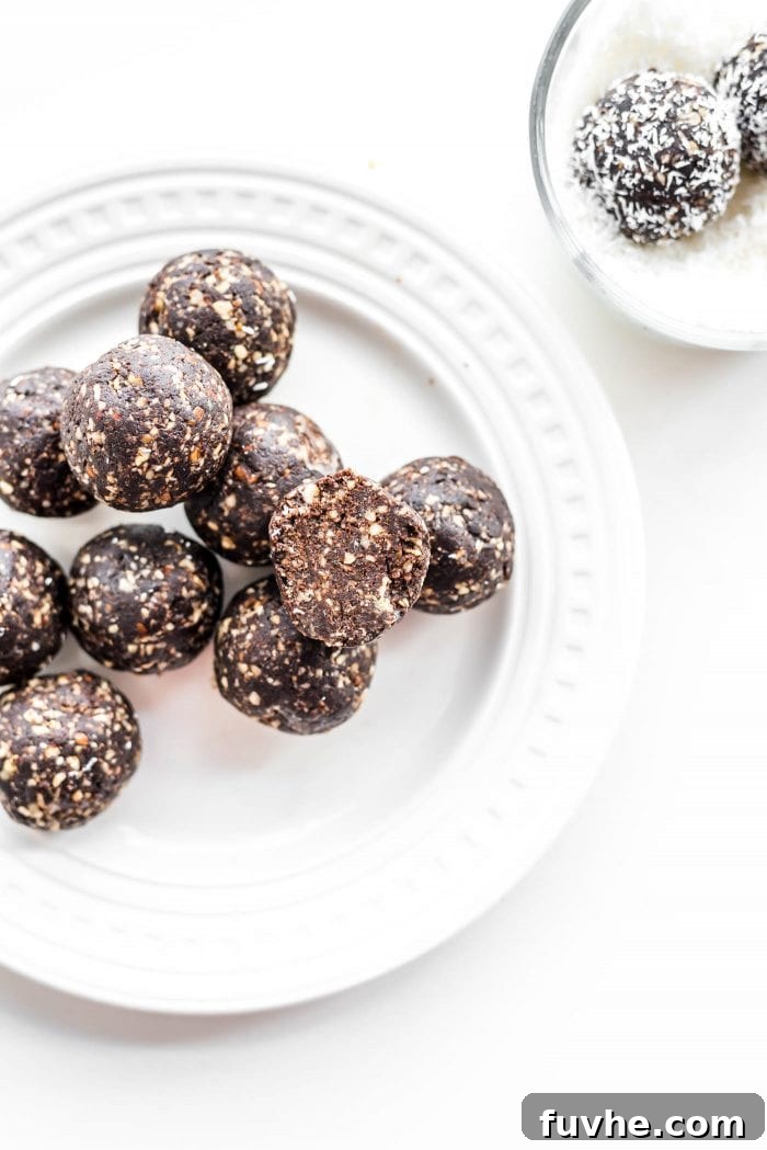 Chocolate raw vegan hazelnut truffles coated in coconut, beautifully arranged on a white plate.