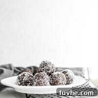 A plate of chocolate balls rolled in shredded coconut sitting on a baking cooling rack.