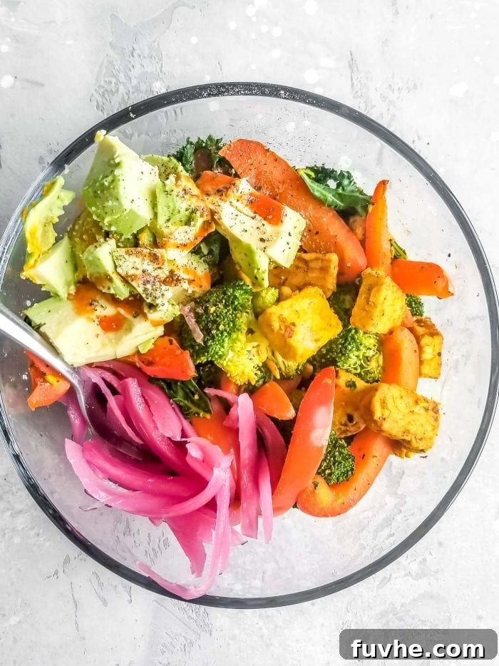 A bowl with broccoli, pickled onion, avocado and bell pepper.