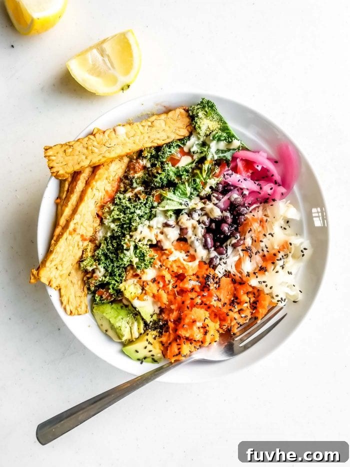 A bowl of kale, avocado, tempeh, pickled onion, black beans and sauerkraut.