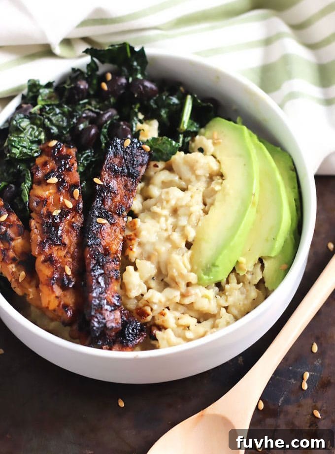 A bowl of oats topped with kale, avocado and tempeh.