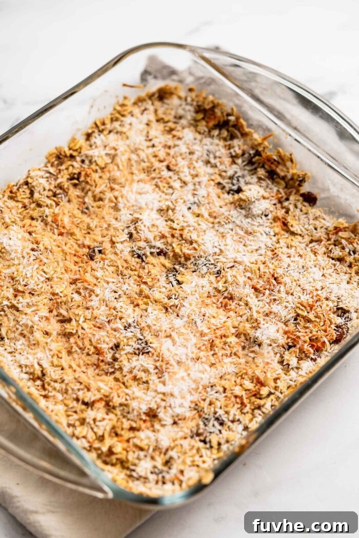 Carrot cake baked oatmeal topped with coconut in a square glass baking dish.