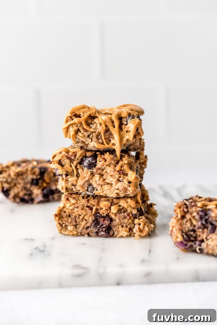 Stack of 3 baked blueberry quinoa oatmeal bars drizzled with peanut butter.