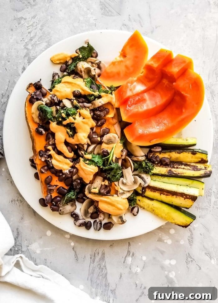 A plate of sweet potato topped with mushrooms and black beans with slices of papaya.