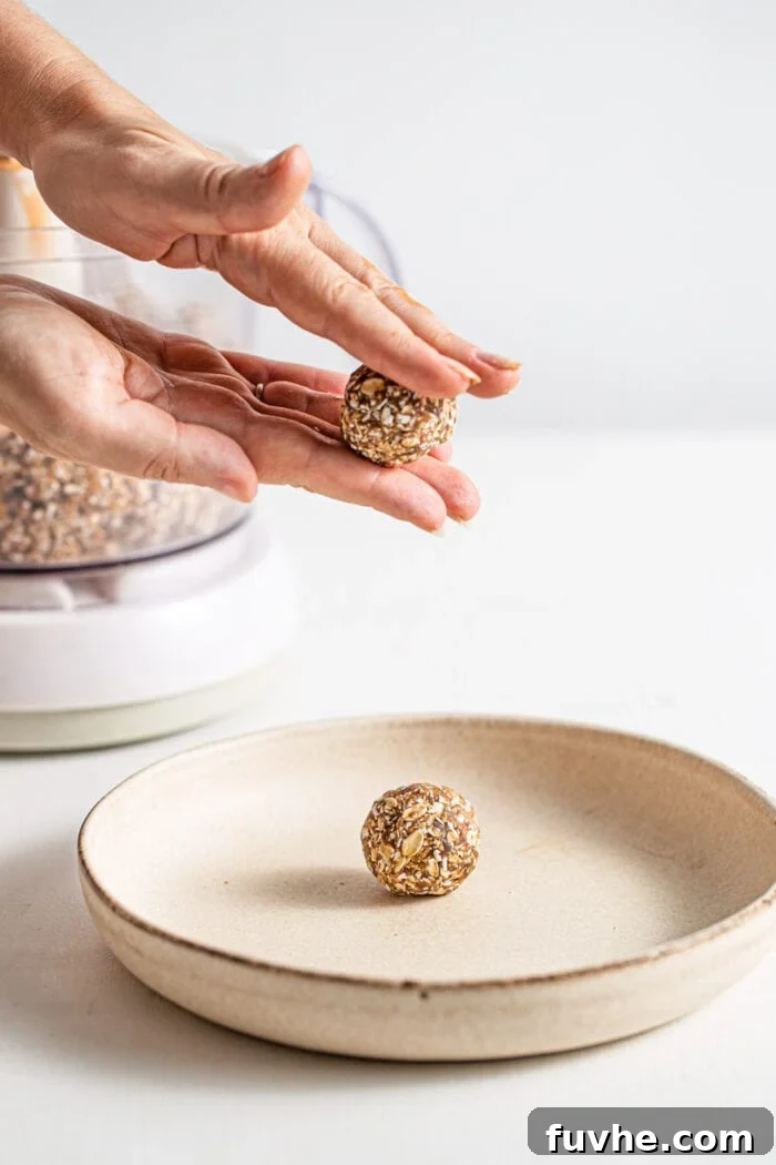 Warm Spice Energy Drops 6 Hands meticulously rolling the energy ball dough into perfect, bite-sized spheres.