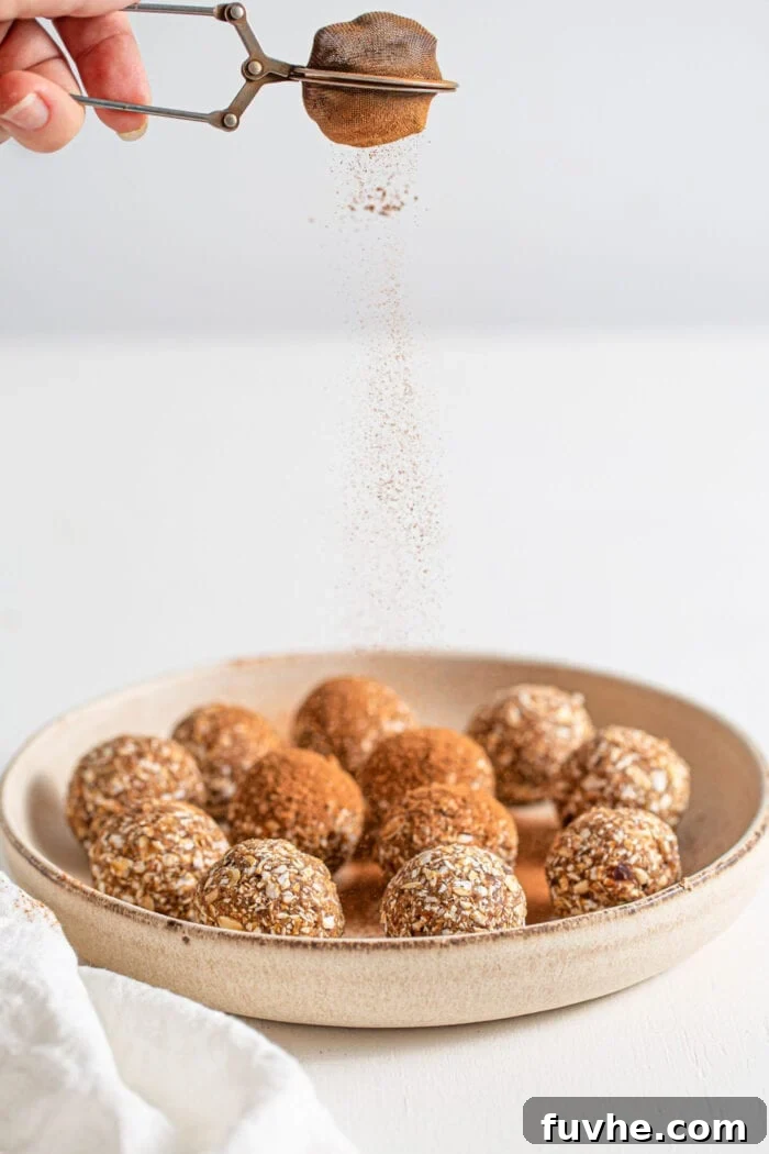 Warm Spice Energy Drops 7 A plate of freshly rolled energy balls being sprinkled with a final dusting of cinnamon.