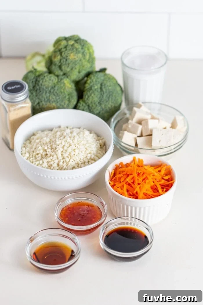 Broccoli, cauliflower rice, carrot, tofu and sauce in containers on a counter.