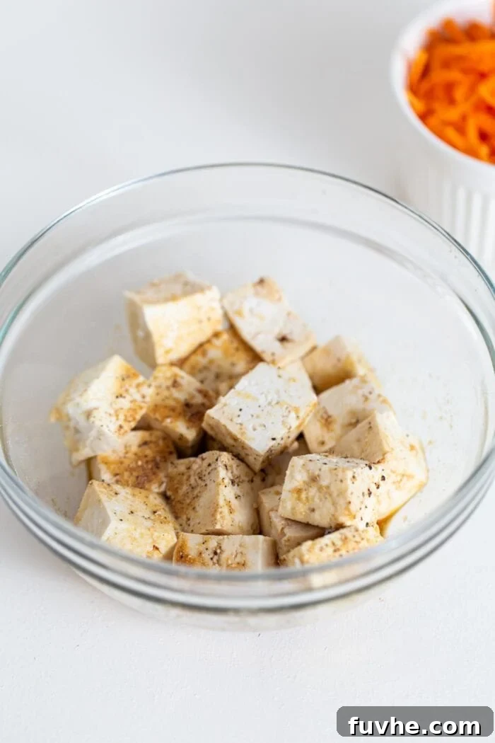 Cubed tofu in a bowl with soy sauce and pepper.