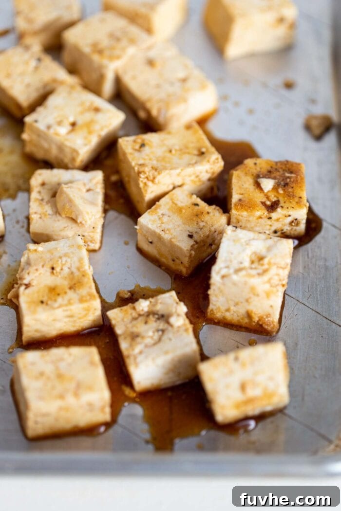 Tofu cubes coated in soy sauce on a baking tray.