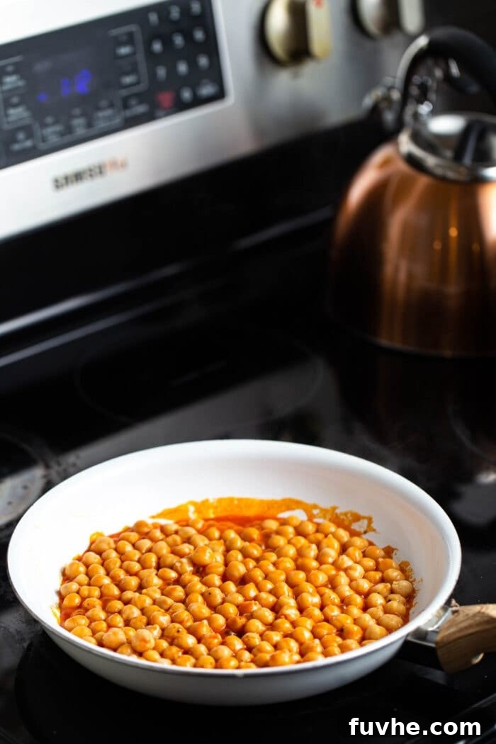 Loaded Buffalo Chickpea Sweet Potatoes 3 A skillet of buffalo chickpeas on a black stovetop.