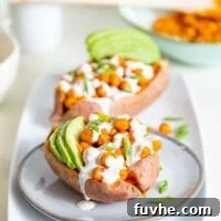 Sweet potato stuffed with buffalo chickpeas and avocado, topped with white sauce.