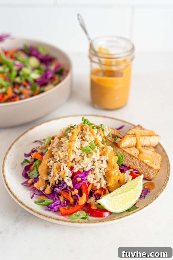 3-Day Plant-Based Whole Food Reset 10 Bowl of colorful salad with brown rice, peanut sauce, tofu and veggies. Jar of sauce in background.