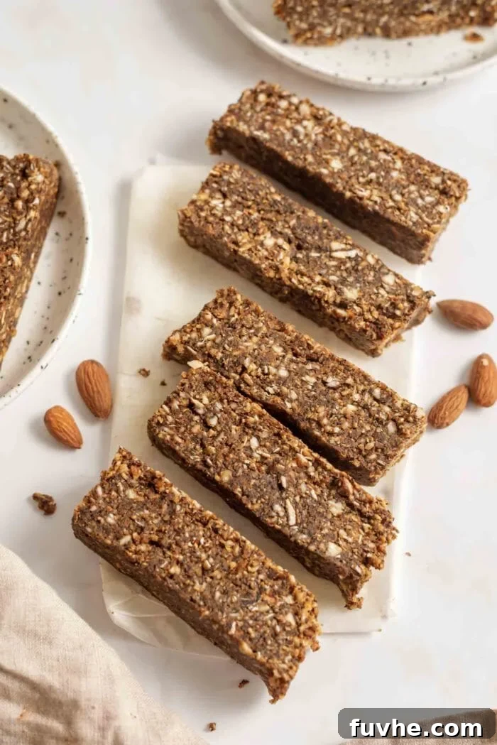 Five thick slices of energy bars arranged on parchment paper with some almonds scattered around, presenting the finished product.