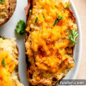 Delicious vegan twice-baked potatoes garnished with melted cheese, fresh parsley, and a sprinkle of paprika, ready to be served as a comforting meal.