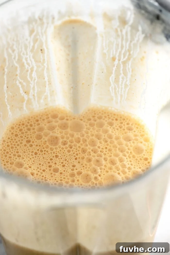 Smooth and creamy blended cashew cream swirling inside a large blender container, showcasing its perfect, velvety consistency.