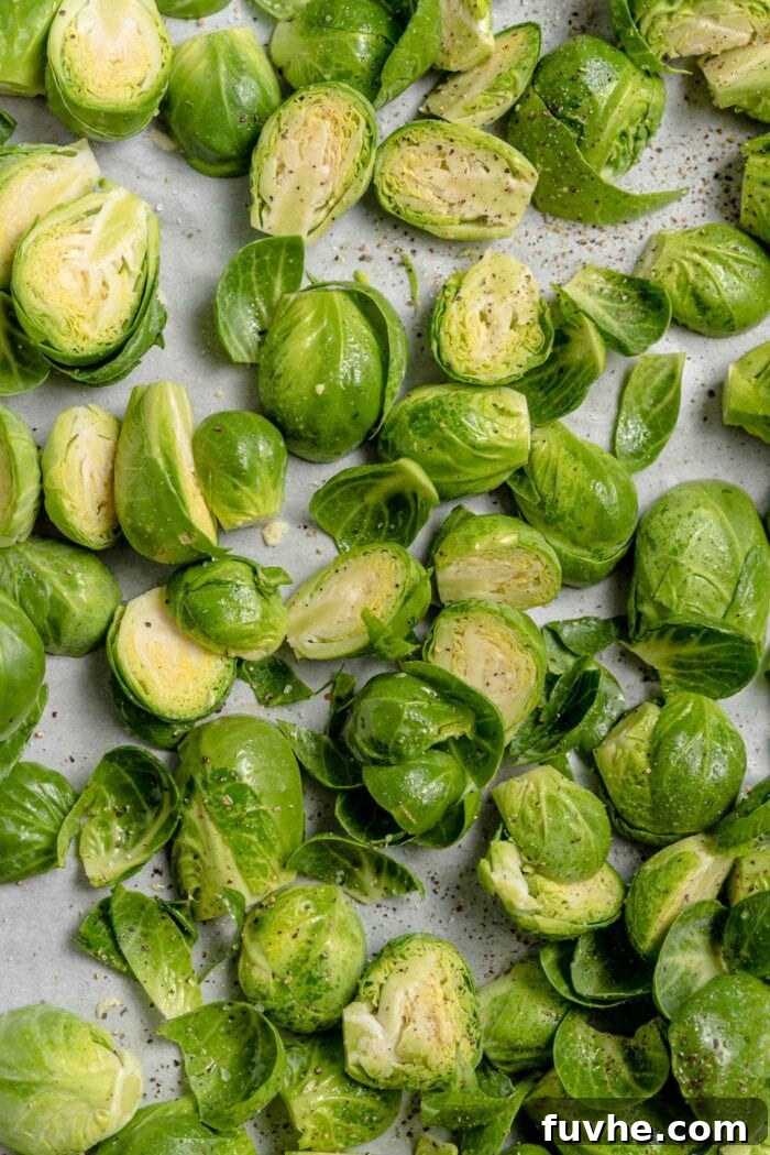 Chopped brussels sprouts on a baking tray lined with parchment paper, ready for roasting.