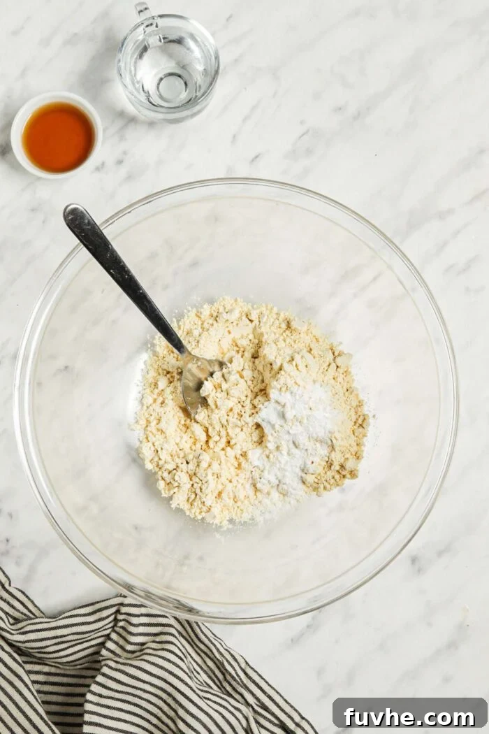 Savory Chickpea Griddle Cakes 4 A close-up view of a clear glass mixing bowl containing chickpea flour, baking powder, and sea salt, perfectly combined and ready for the wet ingredients. The mixture appears light and evenly blended.