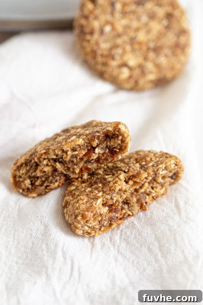 Tahini Date Gems 7 Cookie broken in half to show inside. Cookie rests on a white dish towel.