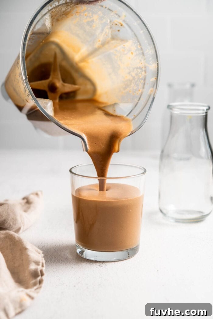 Decadent Tiramisu Smoothie 4 A high-speed blender in action, pouring a rich, creamy chocolate Tiramisu Protein Smoothie into a tall glass, ready to be enjoyed.