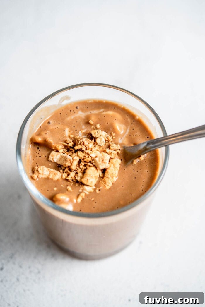 Decadent Tiramisu Smoothie 5 A close-up shot of a rich, chocolatey Tiramisu Smoothie, beautifully presented in a glass with a spoon, topped with a rustic granola or cookie crumble.