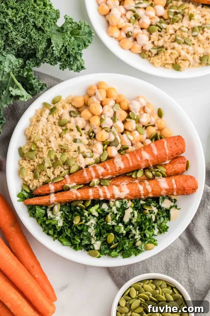 Nourishing Kale Quinoa Chickpea Bowls 2 A vibrant, healthy bowl featuring whole roasted carrots, fluffy quinoa, fresh kale, crunchy pumpkin seeds, and a generous drizzle of creamy tahini dressing.