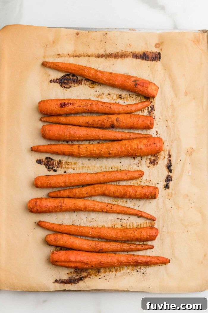 Nourishing Kale Quinoa Chickpea Bowls 4 Whole roasted carrots glistening on a baking tray, perfectly cooked to a tender crisp.
