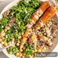 Roasted carrots, kale, quinoa, chickpeas and pumpkin seeds in a bowl topped with tahini sauce.