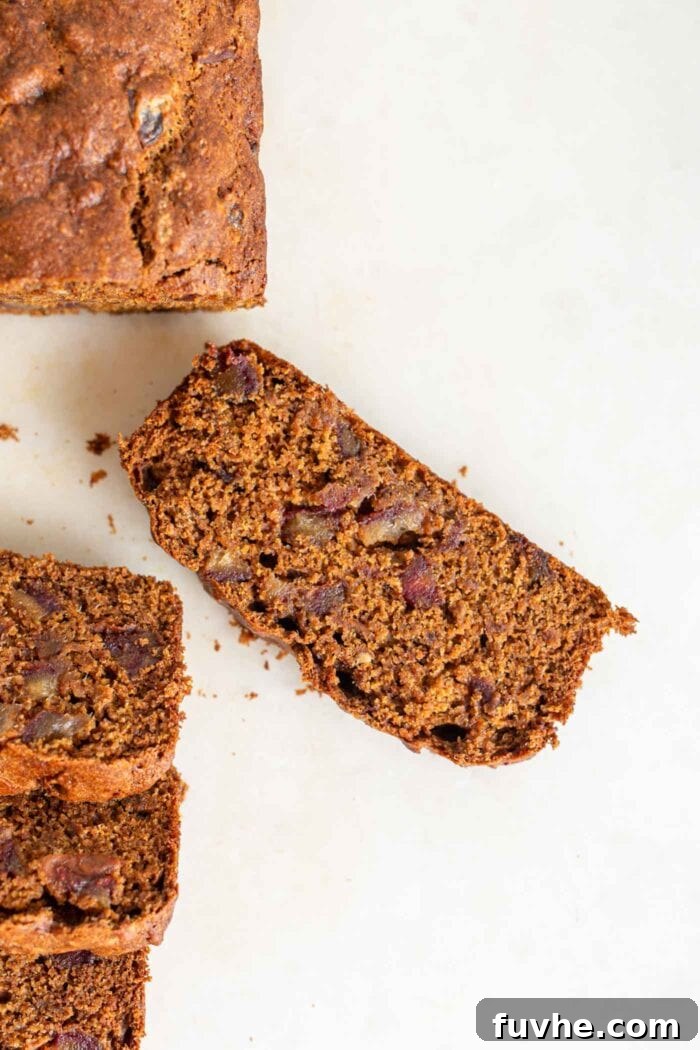 Spiced Vegan Pumpkin Date Loaf 11 A close-up, overhead view of a single slice of moist pumpkin bread, beautifully studded with sweet dates.