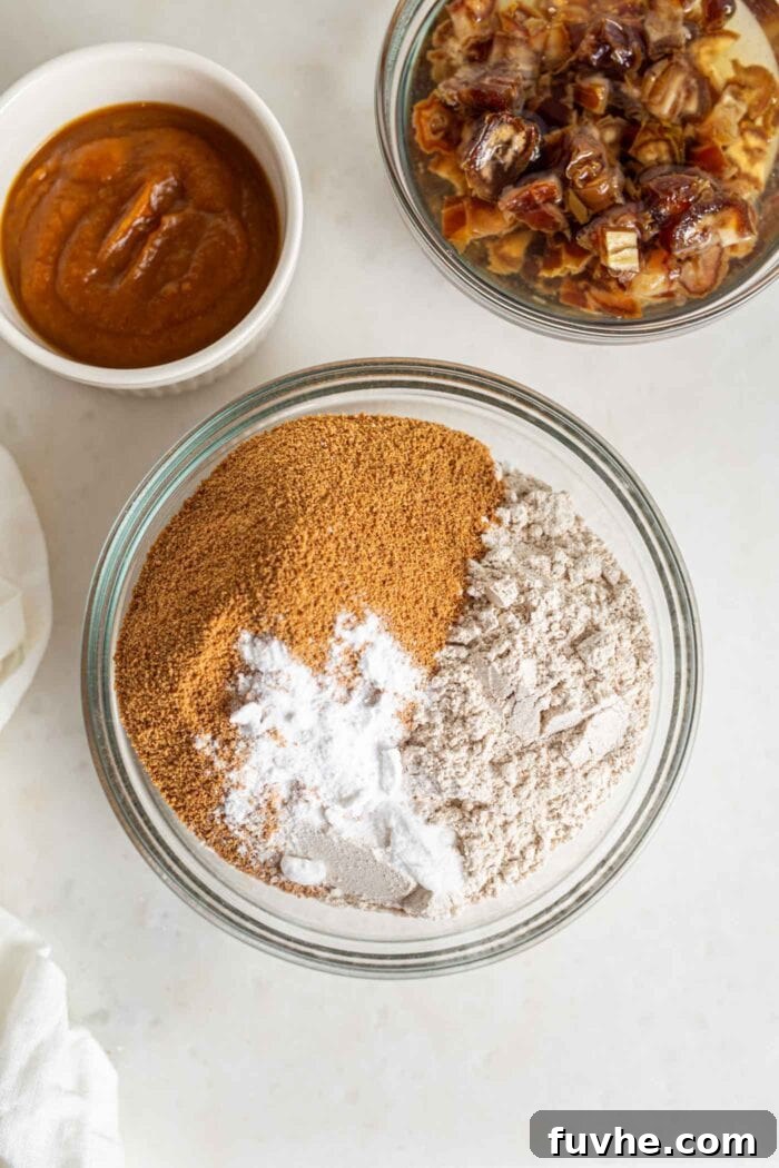 Spiced Vegan Pumpkin Date Loaf 6 Dry ingredients, including flour, coconut sugar, and baking soda, perfectly mixed in a clear glass bowl.