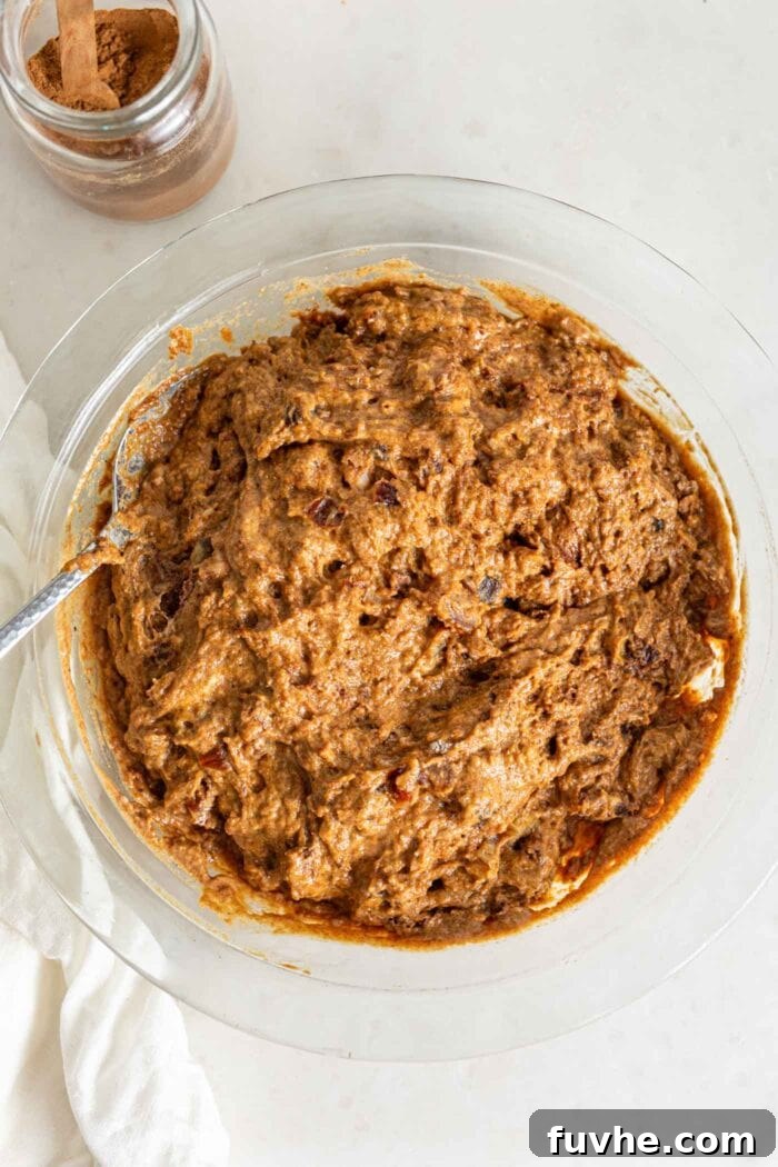 Spiced Vegan Pumpkin Date Loaf 8 A bowl of pumpkin loaf batter with visible pieces of dates, gently mixed and ready for baking.