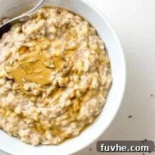 Bowl of creamy oats with banana, topped with peanut butter. A warm and inviting bowl of creamy whole grain porridge, perfectly topped with ripe banana slices and a generous swirl of peanut butter, highlighting its delicious simplicity.