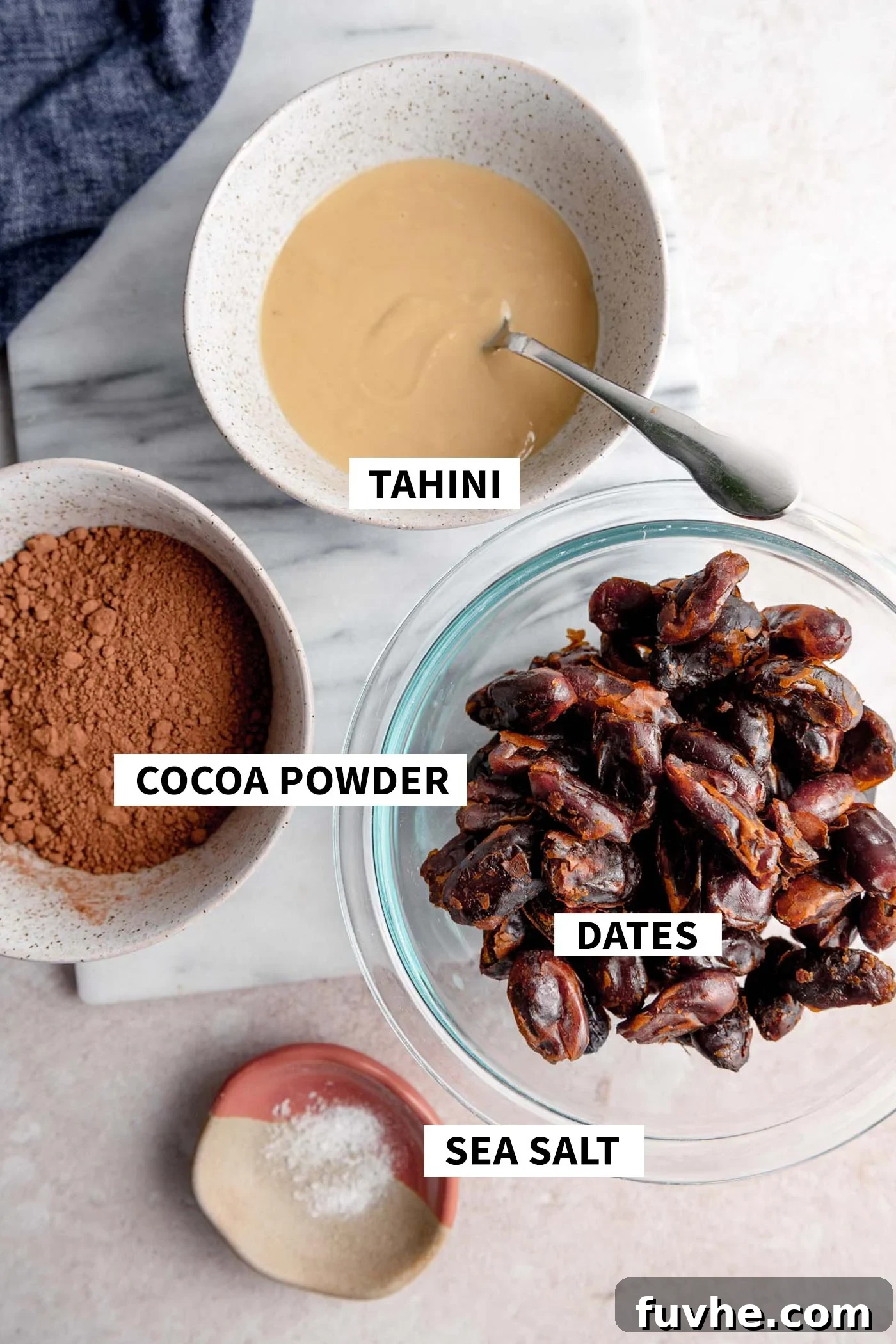 Chocolate Date Truffles 3 Three separate bowls, each clearly labeled: one with rich, dark cocoa powder, another with creamy, light brown tahini, and a third with plump, moist dates, illustrating the three primary ingredients for the chocolate date balls.