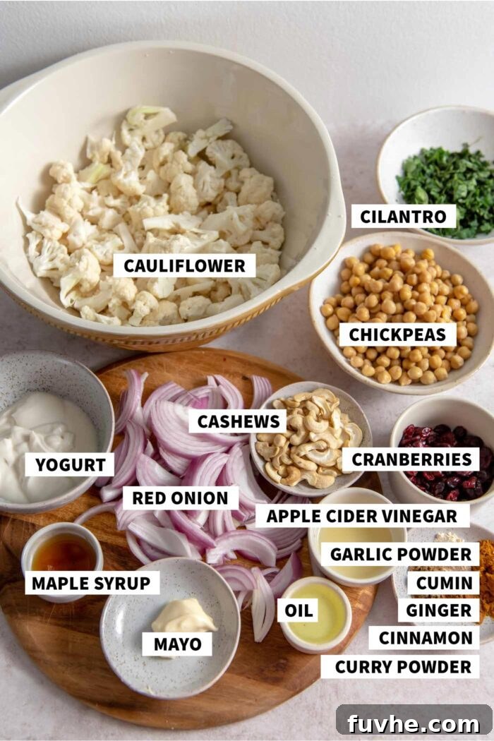 Spiced Cauliflower Power Bowl 3 All of the ingredients needed for making a curry roasted cauliflower salad recipe with cashews, chickpeas, red onion and yogurt dressing. A spread of fresh cauliflower, canned chickpeas, red onion, spices, dried cranberries, cilantro, cashews, and plant-based yogurt and mayo.